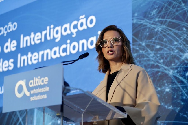 Uma mulher a falar num pódio em frente a um pódio enquanto a Altice Portugal investe 3 milhões de euros em novo Centro de Interligação de Redes Internacionais.