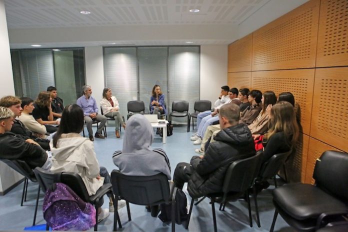 Círculo-de-biblioterapia Um grupo de pessoas sentadas em cadeiras em uma sala, participando do Mês Internacional da Biblioteca Escolar com Círculos de Biblioterapia.