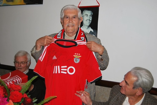 Um homem segura uma camisola de futebol vermelha durante os Festejos do 100.º Aniversário de Jaime João Avelino da Silva.