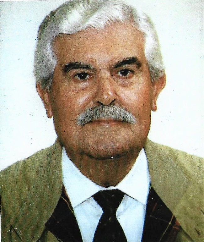 Um homem mais velho, de fato bege e gravata, presente nos Festejos do 100.º Aniversário de Jaime João Avelino da UF da Conceição e Estoi